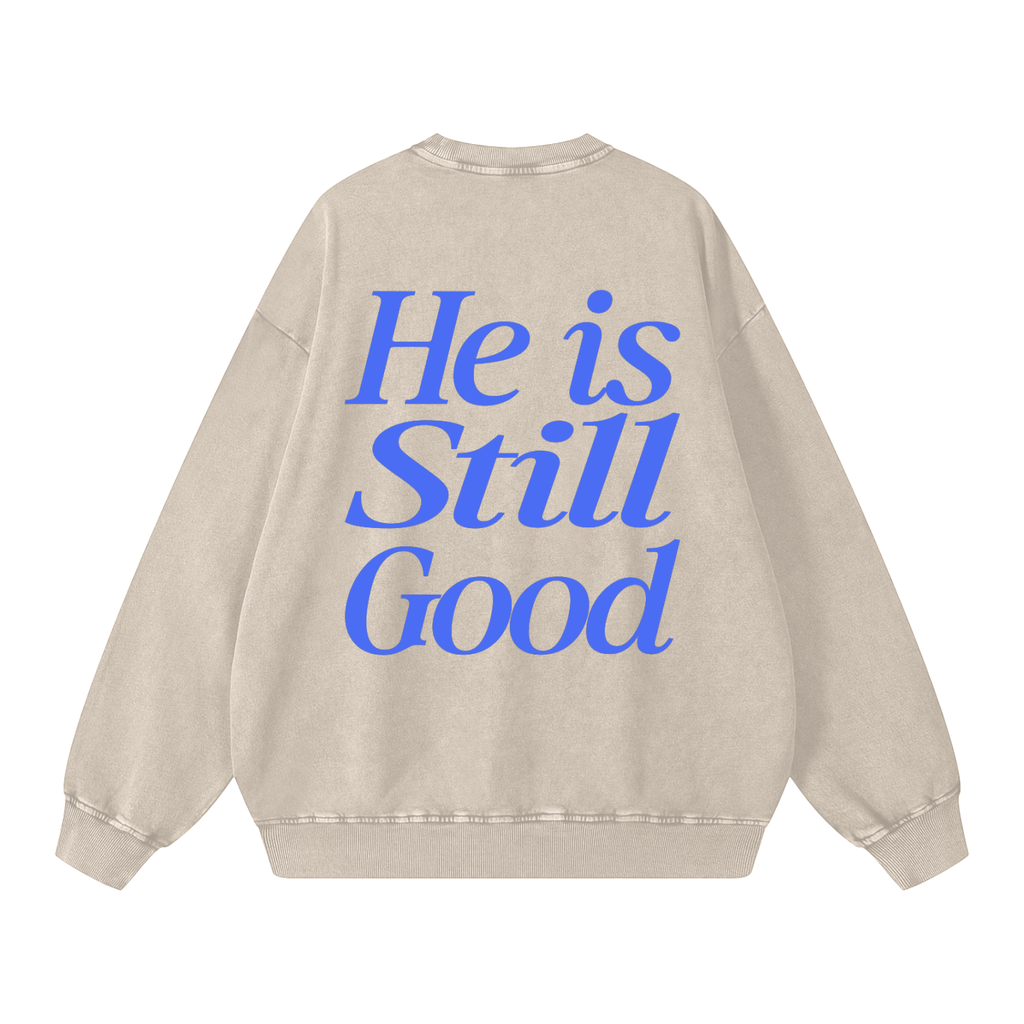 Beige sweatshirt with blue text 'He is Still Good' on a white background